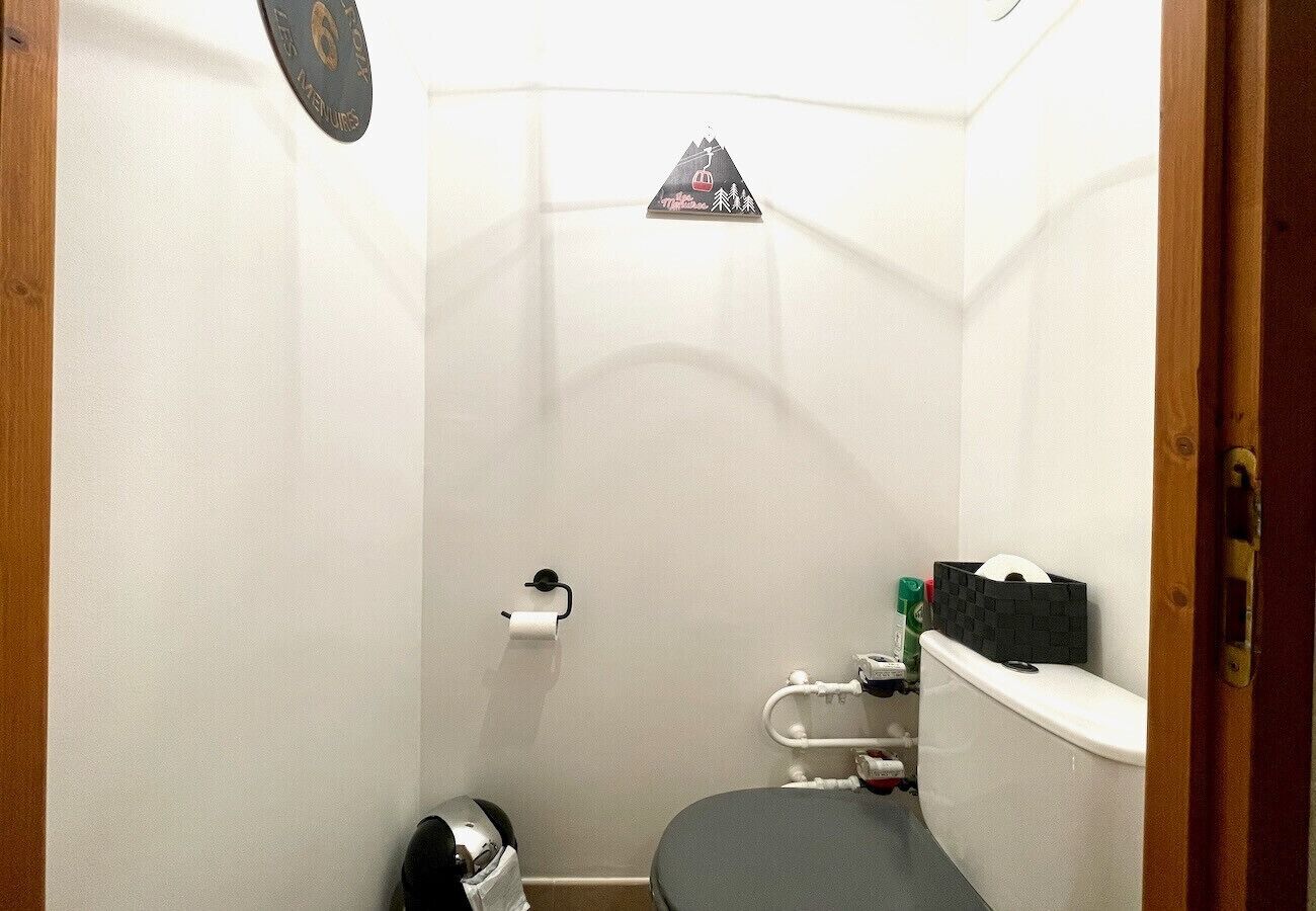 Ein kleines Badezimmer mit Toilette, Handläufer, Seifenspender und Ablagefläche für Toilettenartikel.