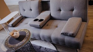 A modern living room with a grey sofa, a glass coffee table, and a small side table.