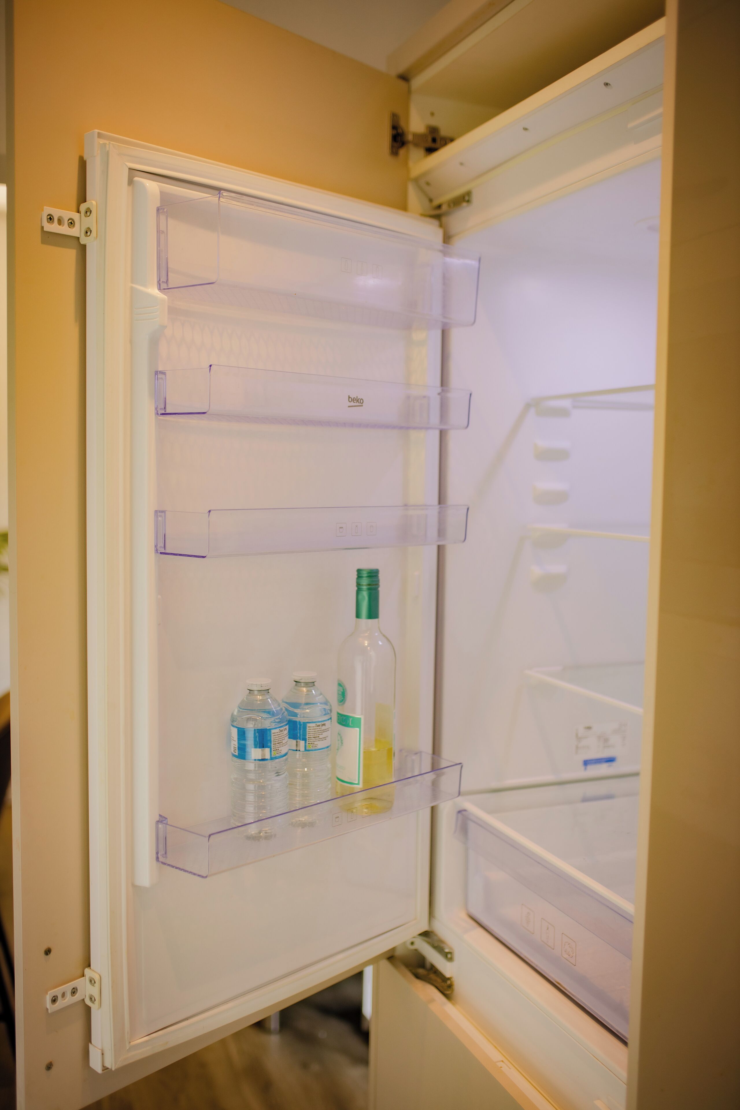 Een open koelkast met heldere plastic planken en een waterdispenser.