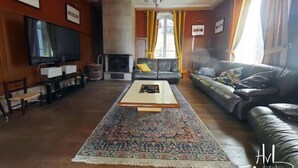 Un salon avec une cheminée, des canapés en cuir, une table basse et un téléviseur.
