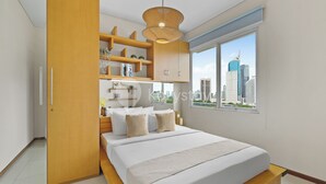 Un dormitorio moderno con cama, estanterías empotradas, vista a la ciudad y un ventanal grande.