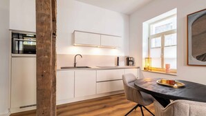 Une cuisine moderne avec des meubles blancs, un plan de travail noir et un coin repas comprenant une table ronde et des chaises.