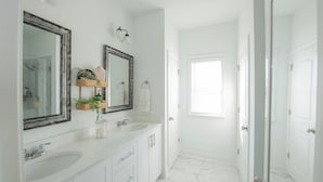 A bathroom with two sinks, a mirror, and a shower.