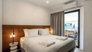 A hotel room with a large bed, a bedside table with a lamp, a balcony with a view, and an air conditioning unit. - Solsalt 1min Walk to Beach 1min From Everything (Platanias)