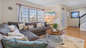 Ein Wohnzimmer mit einem Ecksofa, einem Couchtisch und einem Gemälde an der Wand.