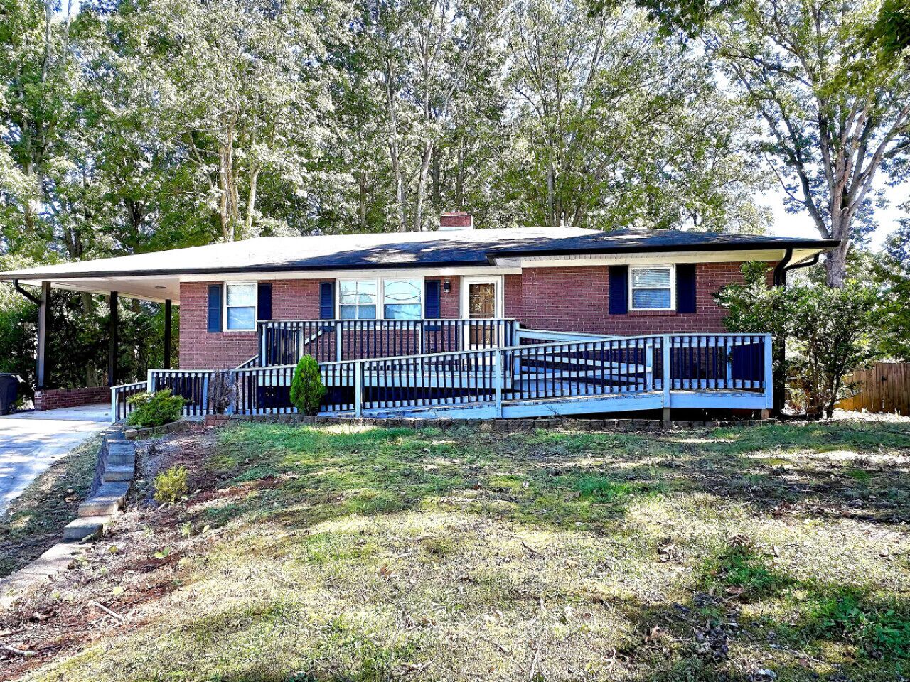 A two-story house with a covered porch, a brick exterior, and a small front yard.