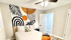 A bedroom with a bed, a ceiling fan, and a door leading to another room.