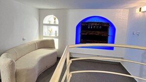 A modern, minimalist room with a curved sofa, a small seating area, and a blue-lit alcove. - Degn'An Holding Residence. (Abidjan)