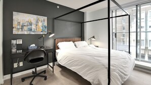 Une chambre moderne avec un lit à baldaquin, un bureau avec une chaise et une grande fenêtre offrant une vue sur la ville.