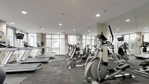 Une salle de sport équipée de plusieurs tapis de course, de vélos elliptiques et de vélos d’appartement, disposés en rangées.