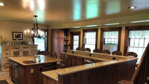 A spacious kitchen with a large island, wooden cabinets, and a chandelier.