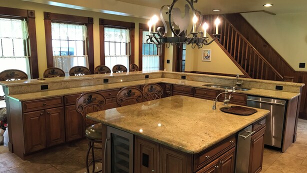 A spacious kitchen with a large island, wooden cabinets, and a stainless steel dishwasher.