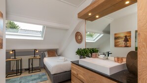 A modern bedroom with a skylight, a large mirror, a bedside table with lamps, a bed, a dresser, and a small plant. - Holiday Home in Zeeland Near the Beach (Biggekerke)