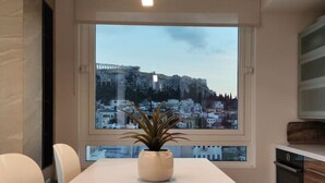 A modern conference room with a large table, chairs, a potted plant, and a view of a cityscape through a large window. - Luxury Acropolis-View Apartment with Panoramic Terrace | Monastiraki (Athina)