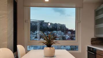 A modern conference room with a large table, chairs, a potted plant, and a view of a cityscape through a large window.