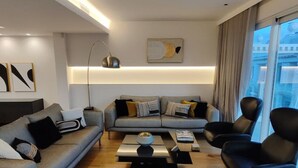 A modern living room with a grey sofa, black armchairs, and a coffee table. - Luxury Acropolis-View Apartment with Panoramic Terrace | Monastiraki (Athina)