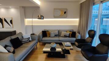 A modern living room with a grey sofa, black armchairs, and a coffee table.