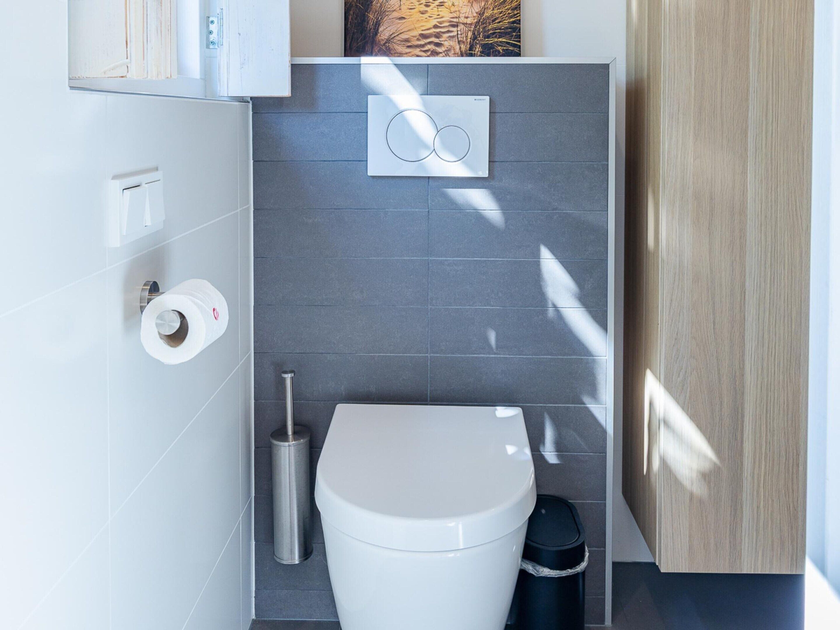 A modern bathroom with a toilet, bidet, and hand dryer.