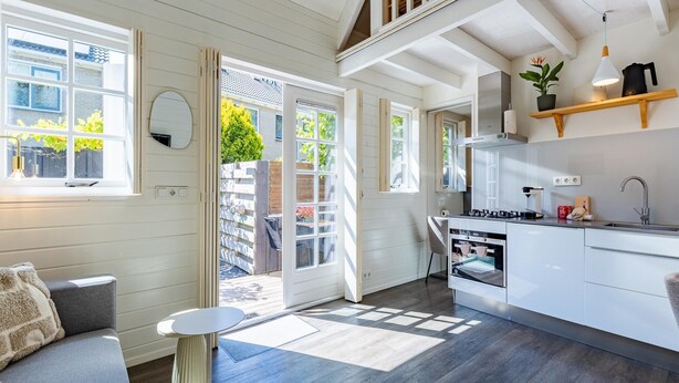 A modern kitchen with a dining area, a staircase, and a view of the outside. - Holiday Home in Domburg Near the Beach (Domburg)