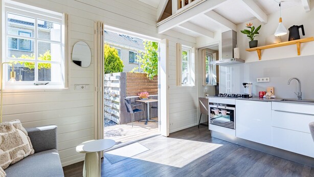 Eine moderne Küche mit Einbauofen, ein Essbereich mit Tisch und Stühlen sowie ein großes Fenster mit Blick auf einen Garten.