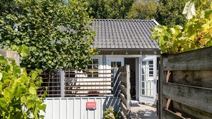 A small building with a tiled roof, a wooden fence, and a welcome sign. - Holiday Home in Domburg Near the Beach (Domburg)