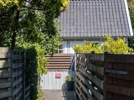 Una entrada cerrada con valla de madera, un letrero de bienvenida y una planta en maceta.