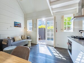 Eine moderne Küche mit Gasherd, ein Essbereich mit Tisch und Stühlen sowie eine Wohnbereits mit Sofa und Gemälde.