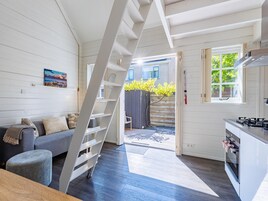 Un interior moderno con una escalera, una cocina y un área de estar con sofá y un cuadro.