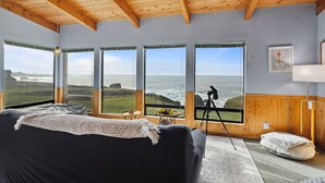 Una habitación acogedora con un ventanal grande con vistas al océano, vigas de madera en el techo y un sofá cómodo.