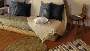 A cozy living room with a sofa, a round mirror, and a small wooden chair. - Studio with garden (Enchastrayes)