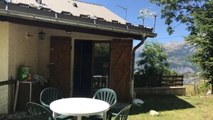 A rustic building with a wooden door and a small table with chairs outside. - Studio with garden (Enchastrayes)