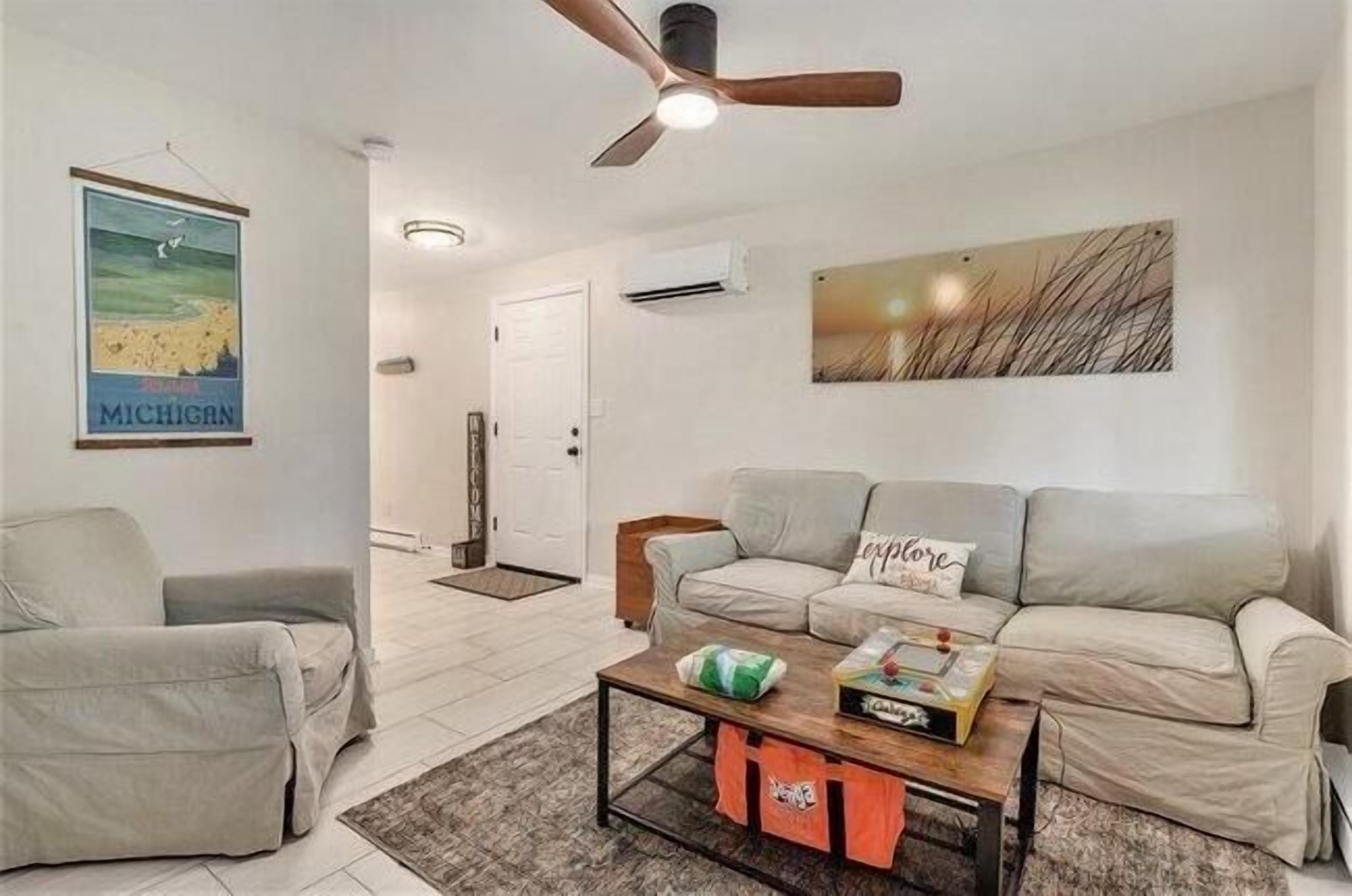 A modern living room with a beige sofa, a coffee table, and a ceiling fan.