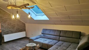 Et moderne loft med skråvægge, en hjørnesofa, et sofabord i glas og et unikt træ sidebord.