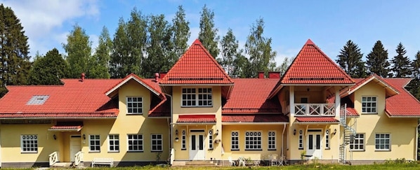 Un edificio de varios pisos con tejados rojos y paredes amarillas, que cuenta con un balcón y un área de estar al aire libre.