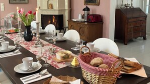 A dining room with a long table set for a meal, a fireplace, and a chandelier. - Wiisalan Kartano (Rantasalmi)