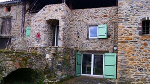 A stone building with a rustic appearance, featuring a small arched entrance and a door with green shutters. - House "Les sauvages" - Nature and charm on the banks of the Allier 8 to 10 people (Blassac)