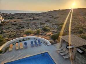 Zona de piscina con tumbonas y una piscina pequeña, con vistas a un paisaje árido y al mar.