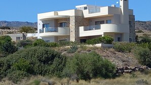 Une maison moderne à deux étages, dotée d’une façade en pierre, de nombreux balcons et offrant une vue sur le paysage environnant.
