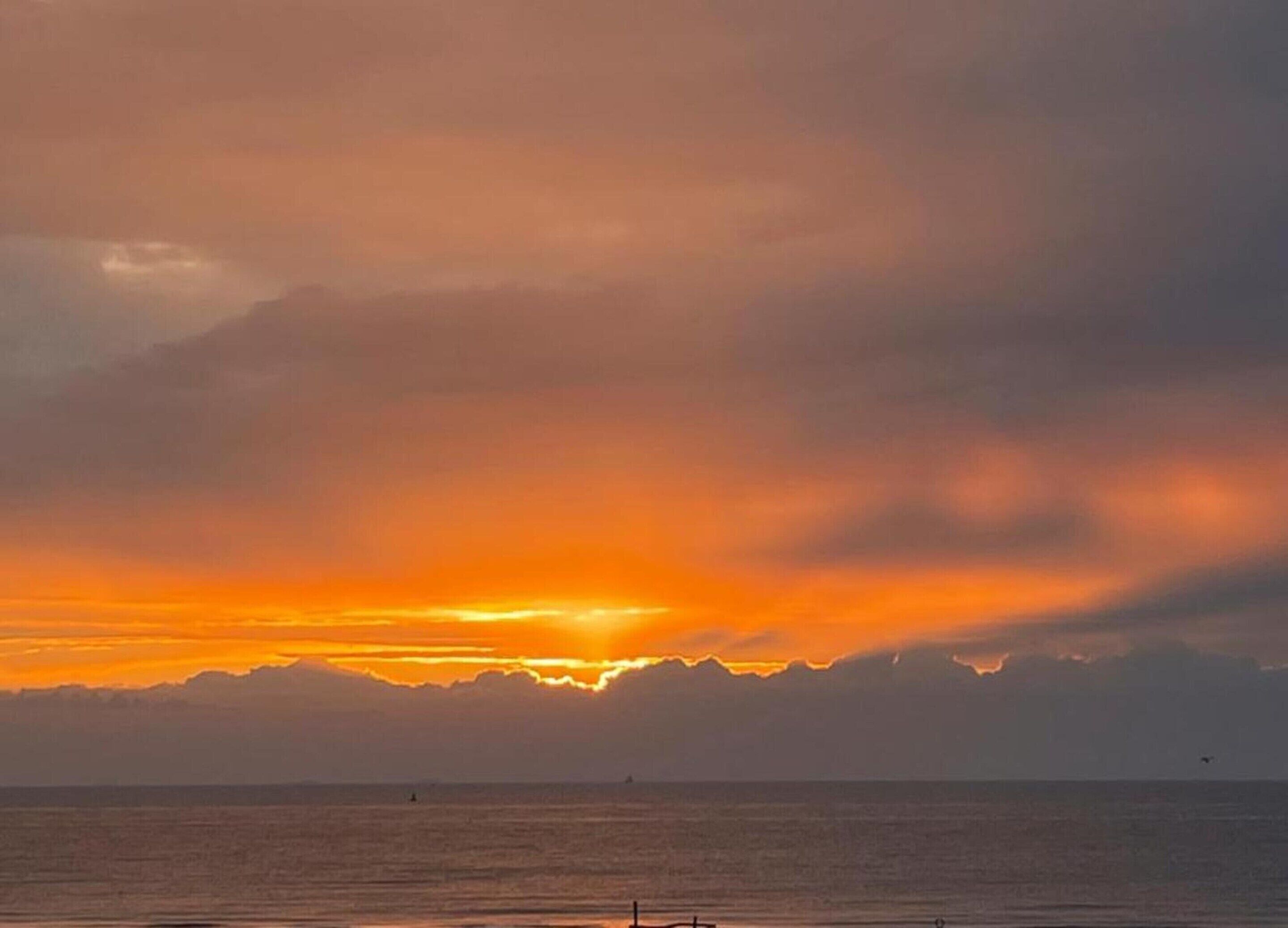A sunset over a body of water with a distant mountain range.