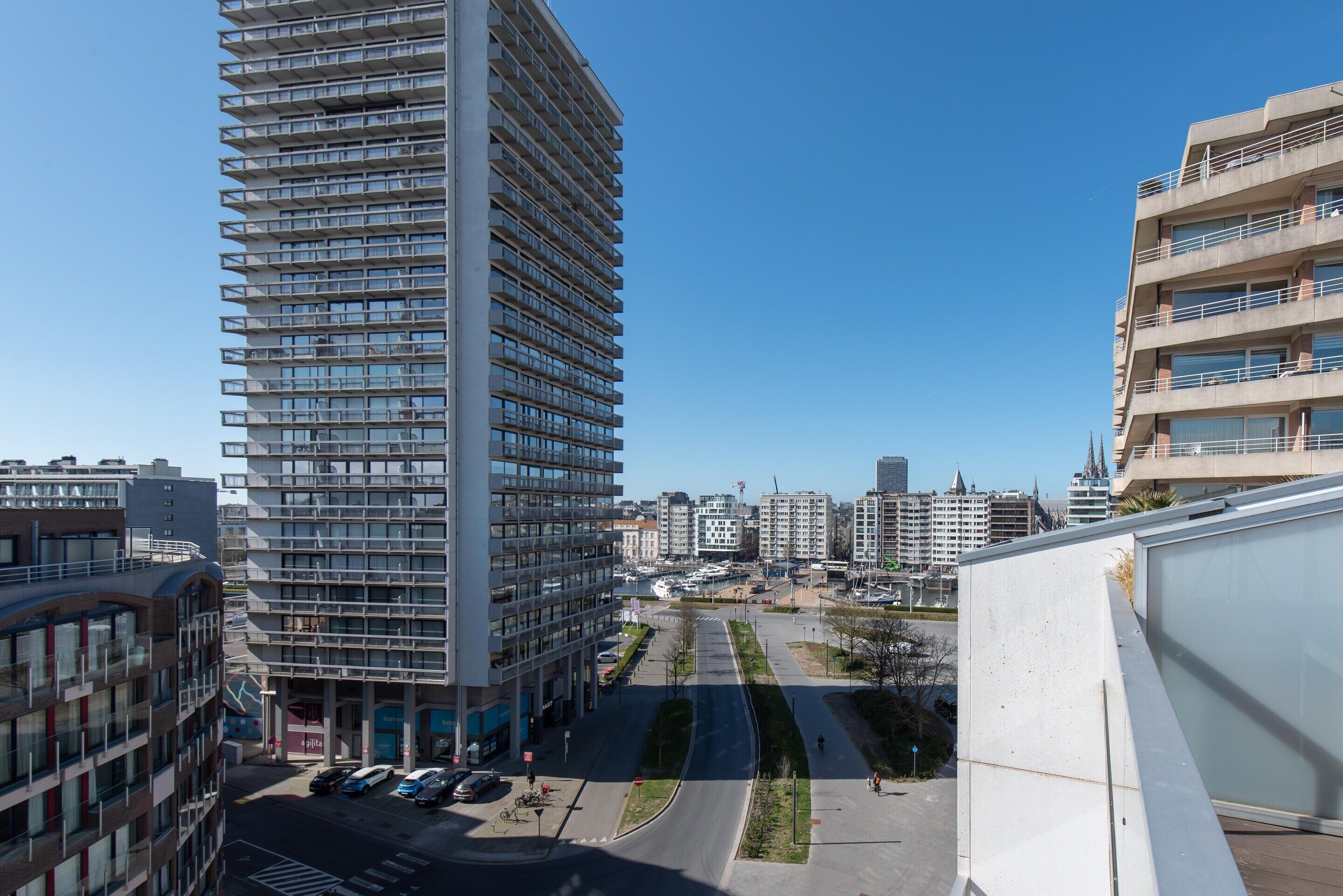 A modern high-rise building with multiple balconies and a clear view of the surrounding urban area.