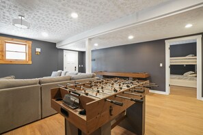Ein modernes Wohnzimmer mit einem Kicker, einer Couch und einem Holzkabinett.
