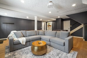 A modern living room with a grey sectional sofa, a round coffee table, and a staircase leading to another level.