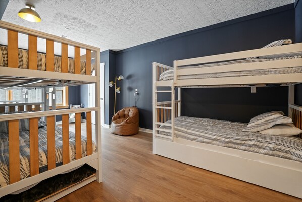 A bunk bed room with a bean bag chair, a ceiling light, and a wall-mounted lamp.