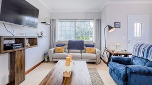 A living room with a TV, sofa, coffee table, and a window with curtains.