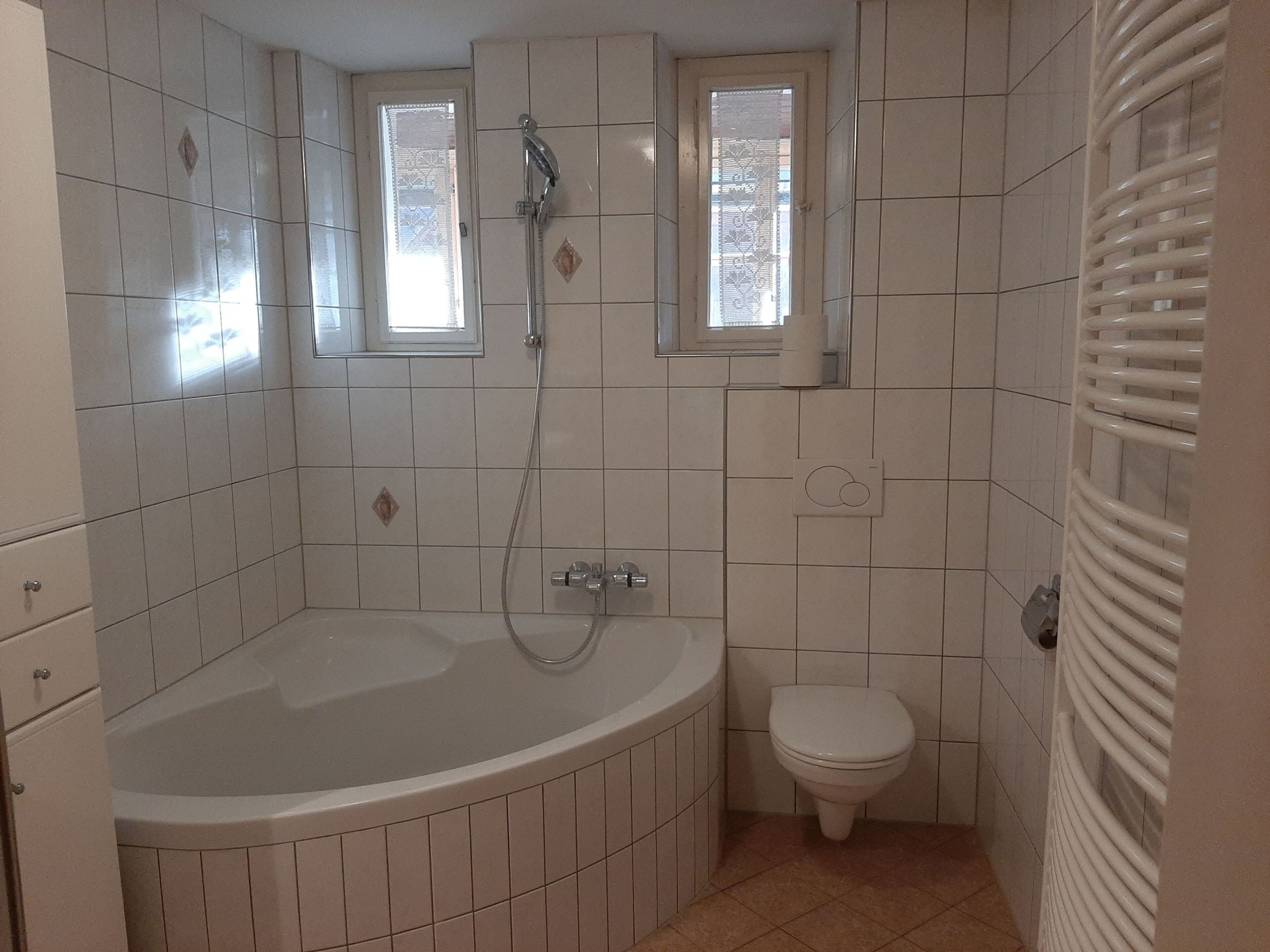 A bathroom with a bathtub, a toilet, and a window.