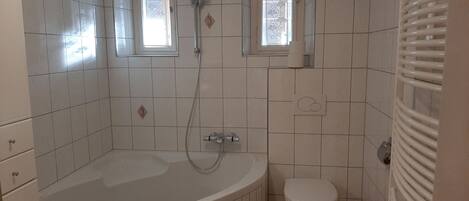 A bathroom with a bathtub, a toilet, and a window.