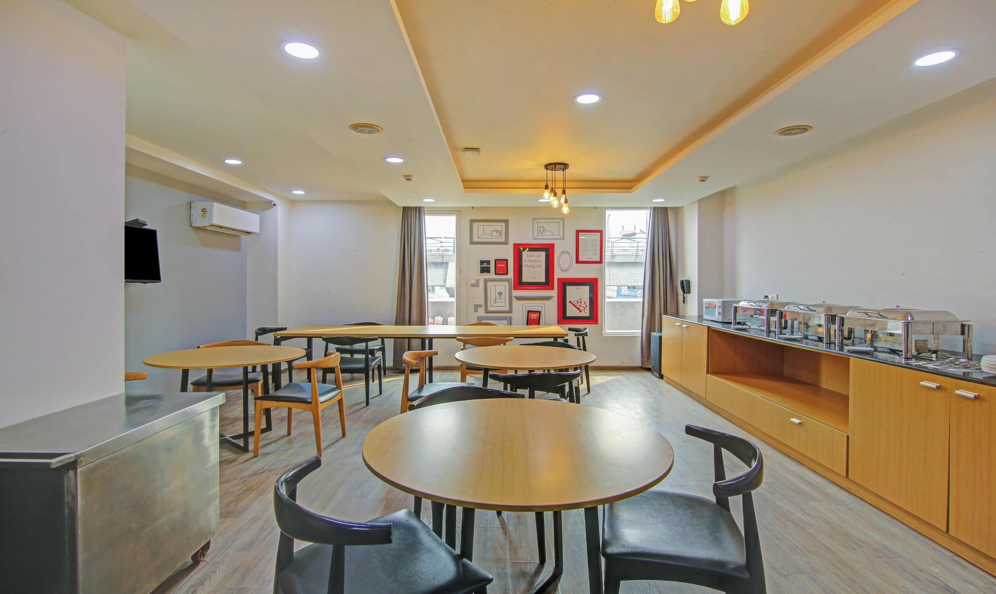 A dining area with multiple tables and chairs, a buffet counter, and framed pictures on the walls.