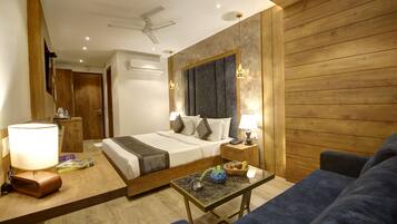 A hotel room with a bed, a desk, a chair, a ceiling fan, and wooden walls.
