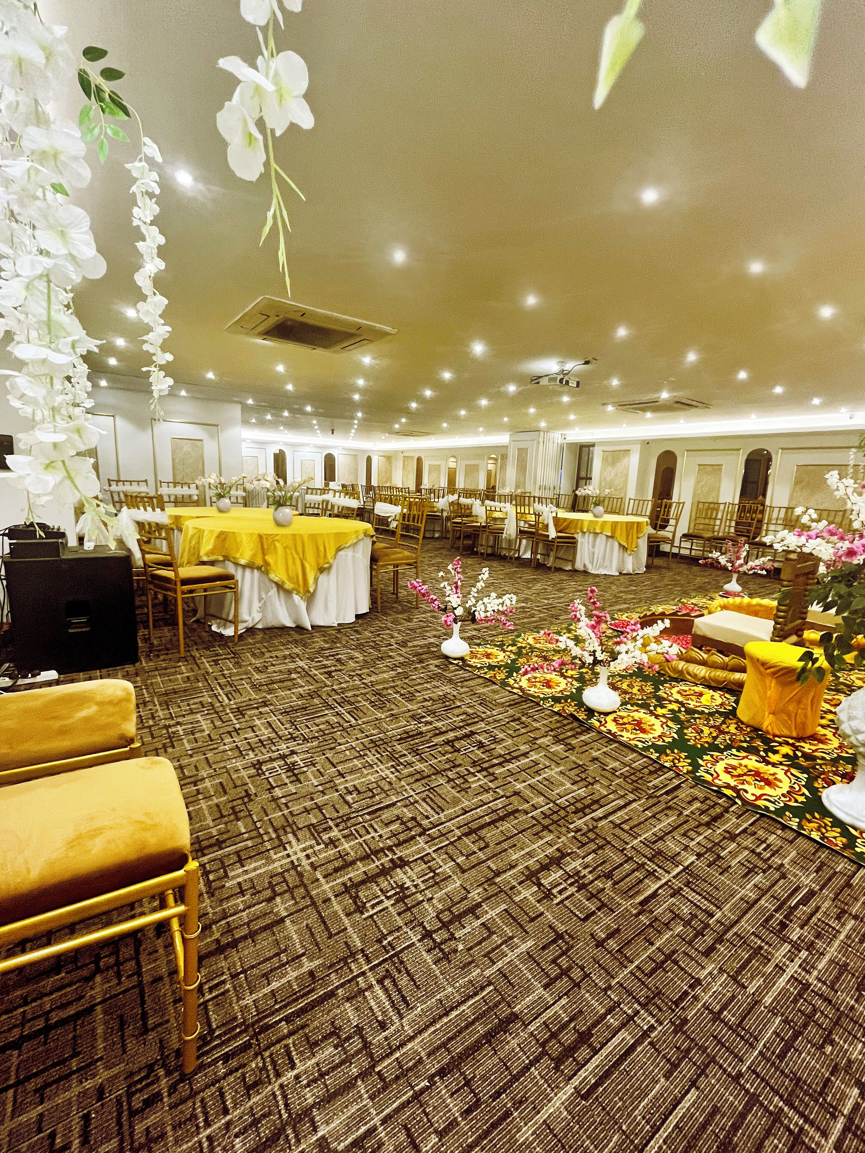 A banquet hall with tables set for dining, chairs arranged around them, and floral decorations on the floor.