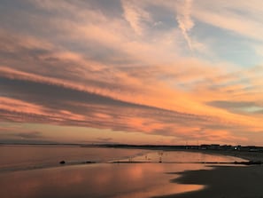 A beach with a calm sea, a pier, and a distant shoreline with buildings. - Luxury Oceanfront Condo - 2BR / 2BA + Office - June & July Month-Long Stays (Hampton)